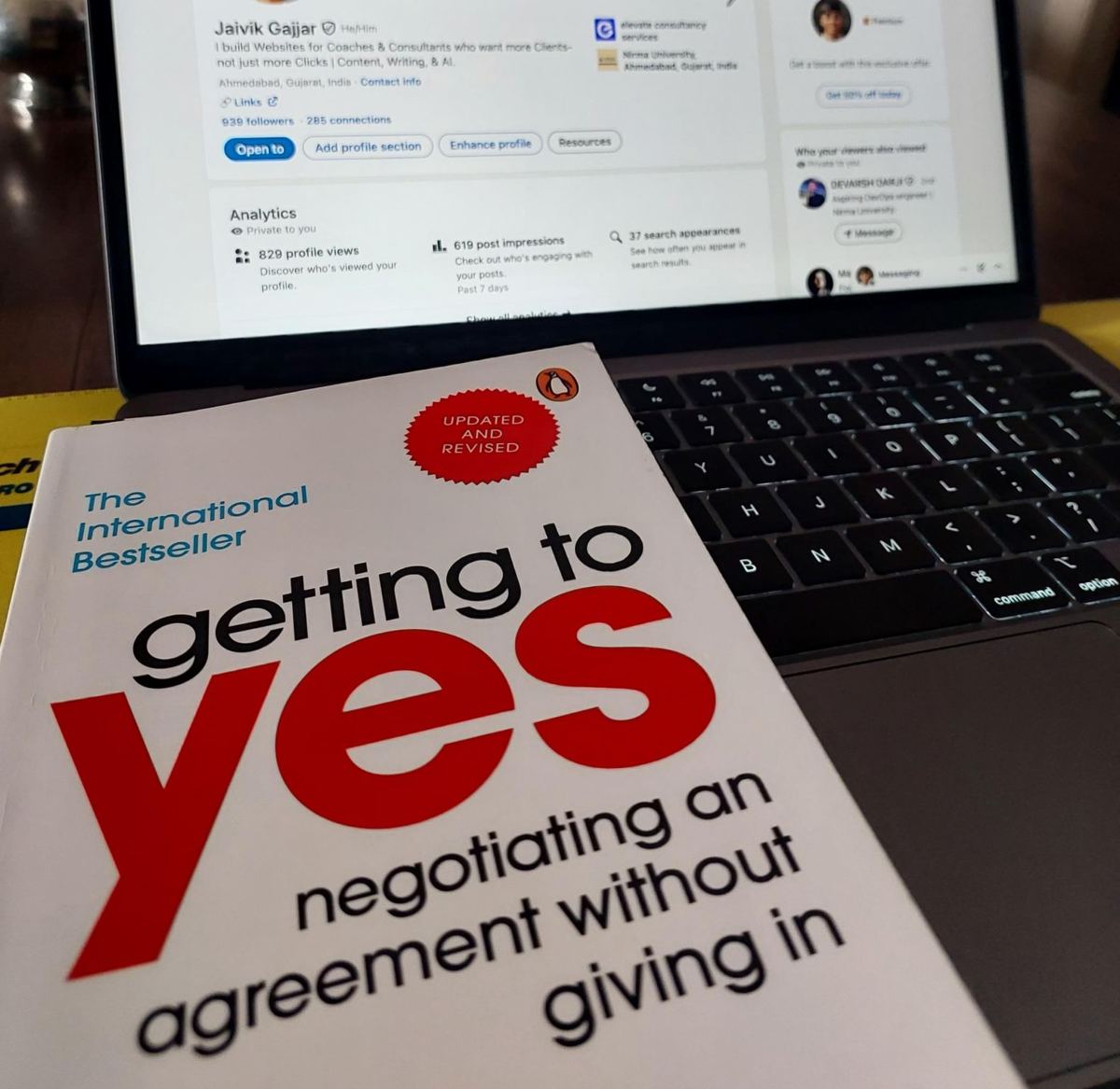 LinkedIn open on my laptop, next to a book on negotiation